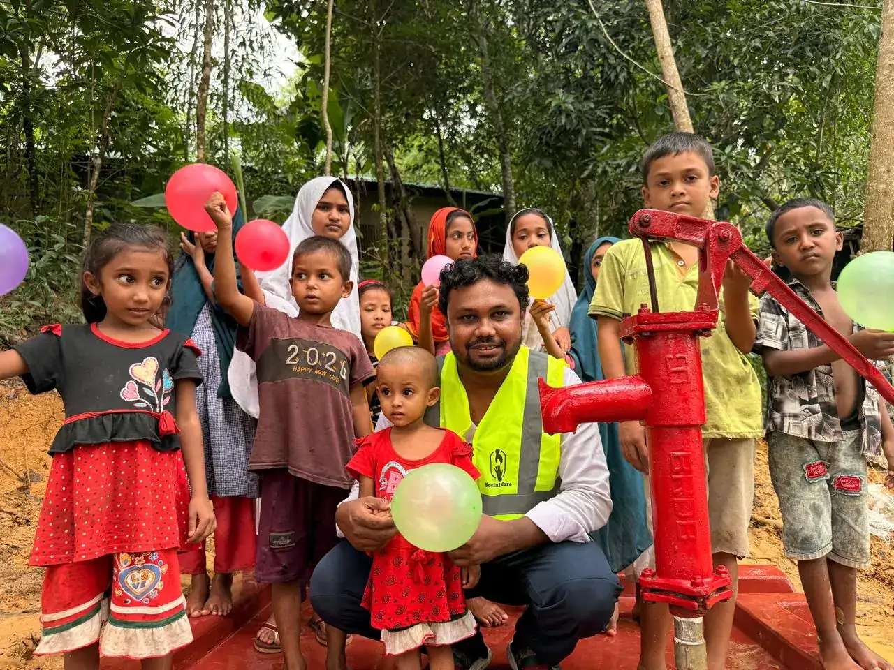 Social Care team member with children at a new tubewell in Cox's Bazar